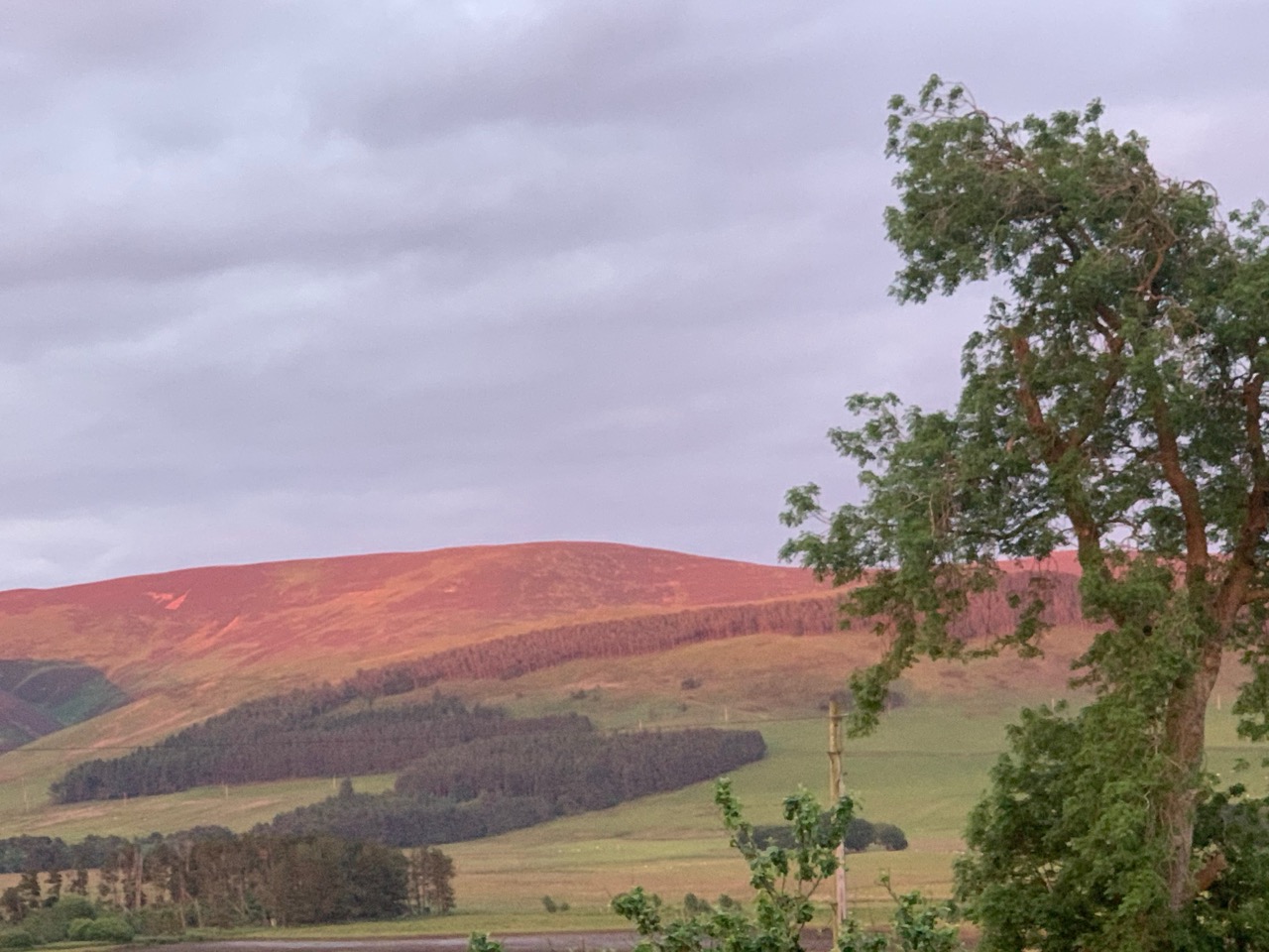 Hill summit glowing deep red and orange in dramatic sunset light